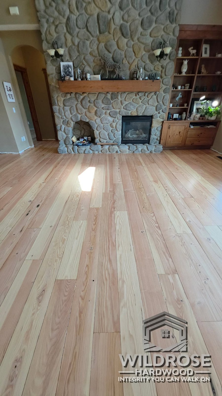 Fir hardwood floor resanded to natural finish, stone fireplace living room, real customer job by Wildrose Hardwood Calgary Airdrie